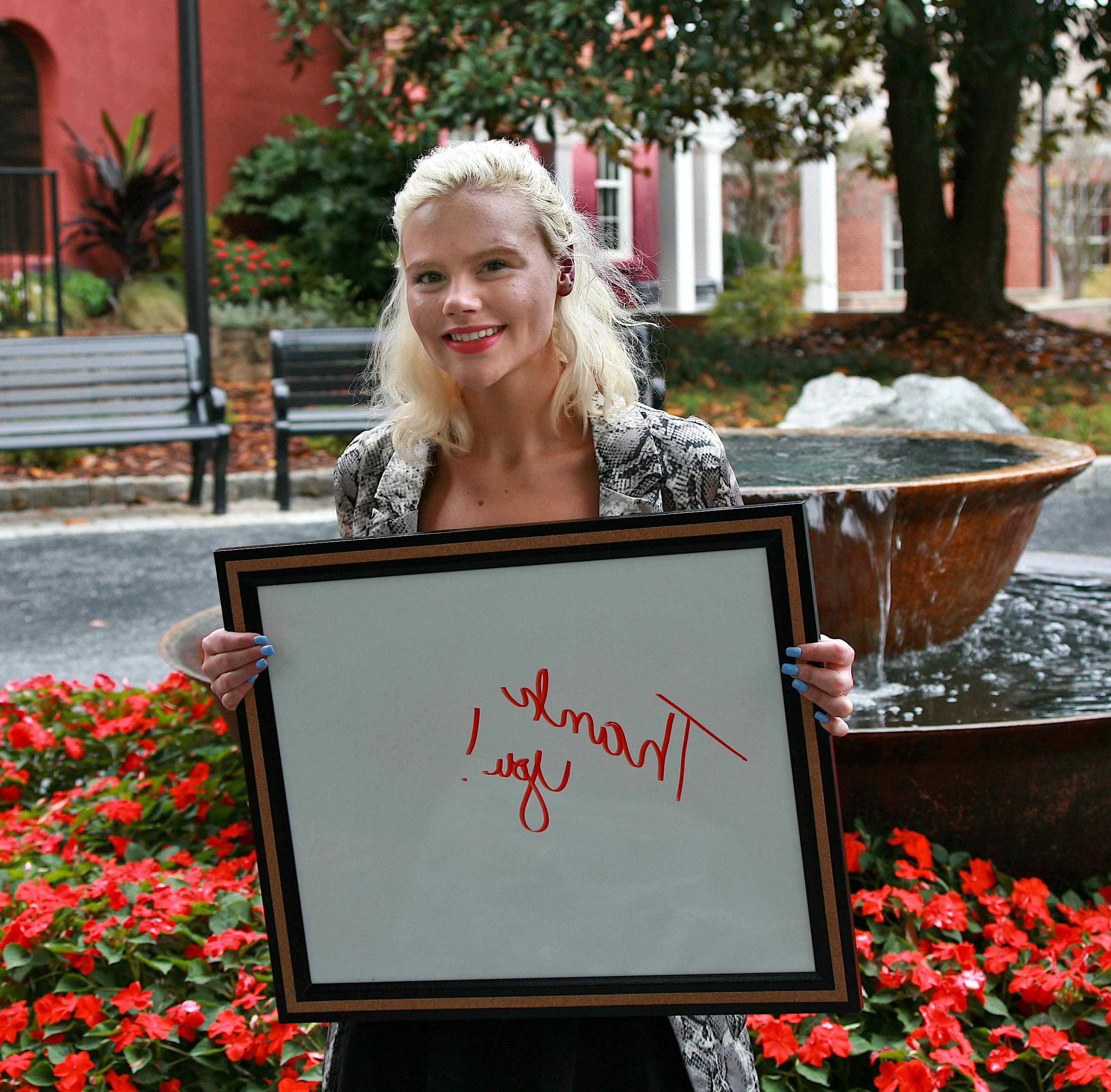 Young female adult holding a sign that says "Thank you!"